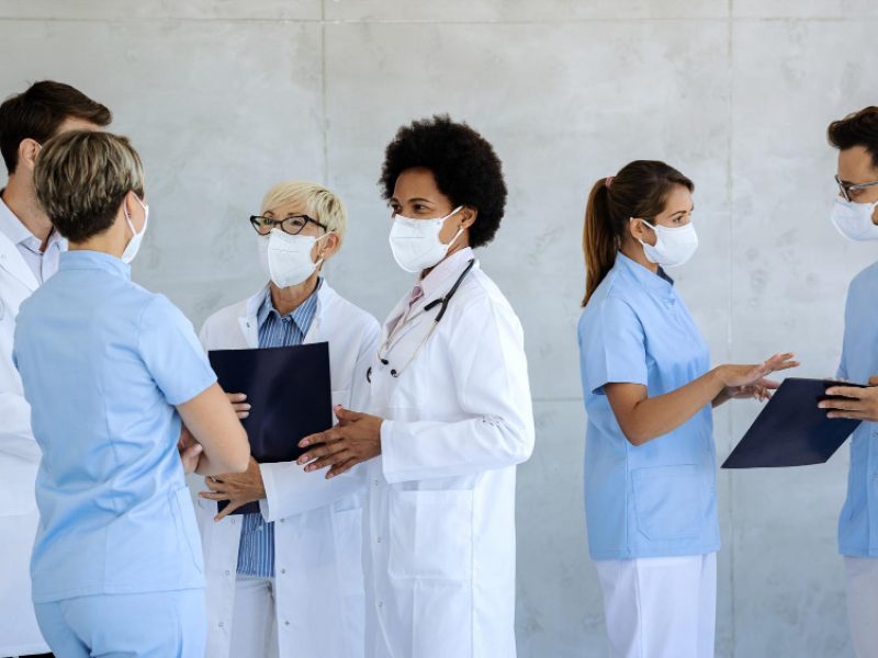 group-healthcare-workers-with-protective-face-masks-talking-hospital-hallway